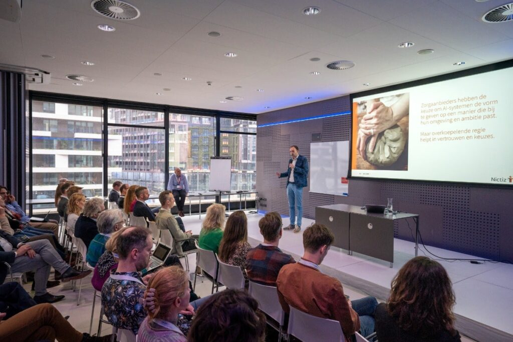 Tim Postema van Nictiz staat op het podium tijdens zijn presentatie op het event Large Language Models in de zorg van januari 2024 met Health-RI.